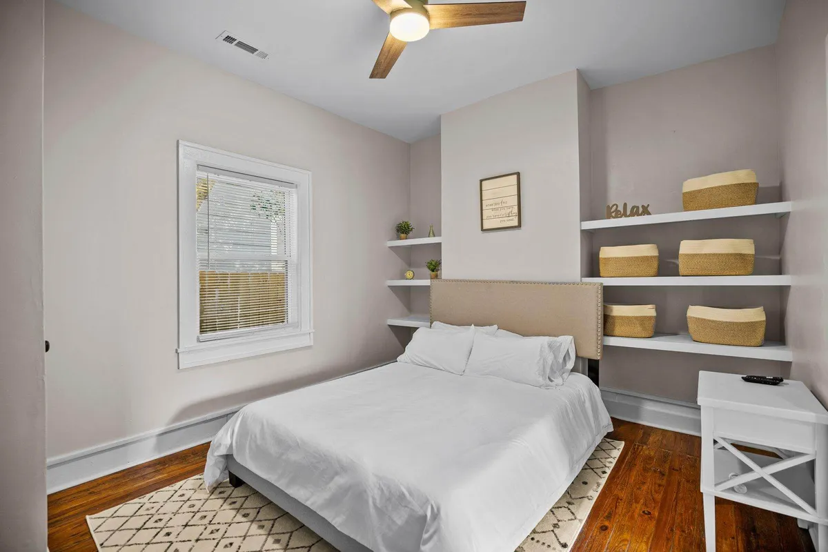 This image features a serene bedroom with a comfortable bed, shelves adorned with decorative baskets, and a window that lets in natural light, creating a calm and restful atmosphere. The setting is uncluttered and tranquil, embodying the retreat-like quality mentioned in the section.