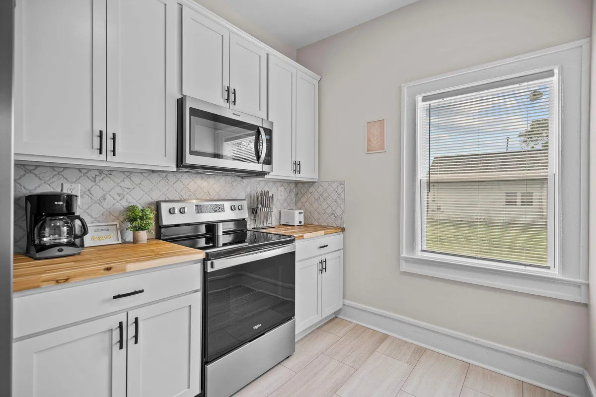 A kitchen bathed in natural light, showcasing stainless steel appliances, wooden countertops, and a window. The inviting setup is perfect for casual dining and family gatherings.