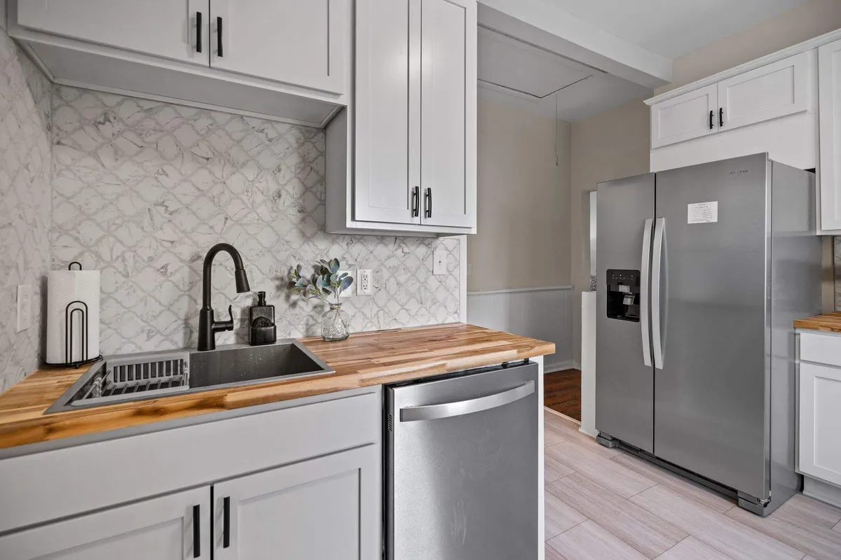 A welcoming kitchen with a wooden countertop, stainless steel appliances, a decorative plant, and a modern faucet. The space is bright and functional, designed for cooking and gathering, with clear attention to modern design details.