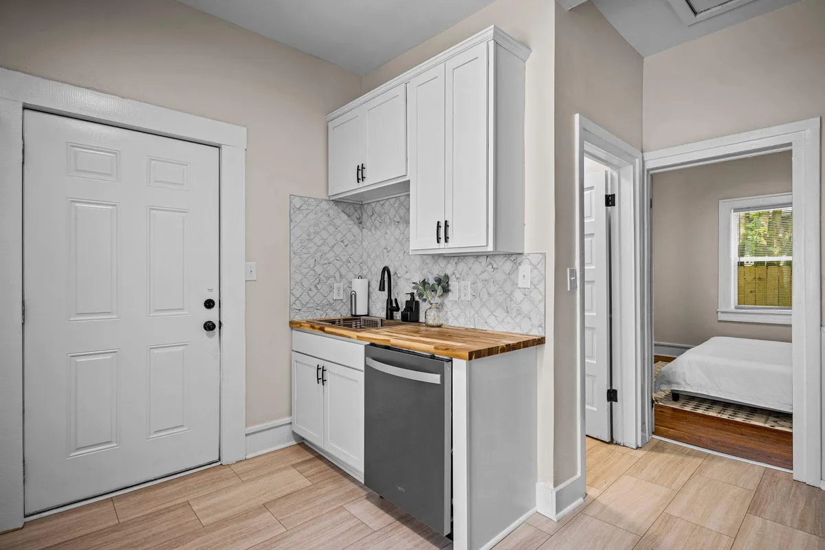 A cozy kitchenette with a wooden countertop and stylish backsplash tile, inviting guests to gather, cook, and socialize. The intimate scale suggests an ideal setting for late-night snacks, pre-dinner drinks, or brunch after a night out.