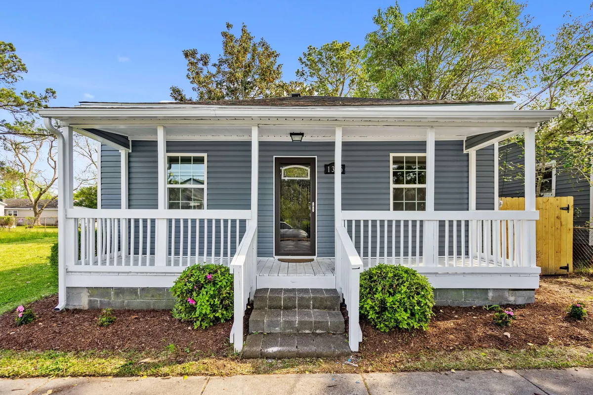 This image captures the home's front porch, main entrance, and a landscaped garden, presenting a welcoming exterior setting. The porch offers space for relaxation or conversation, and the surrounding greenery adds to the sense of arrival and homeliness.