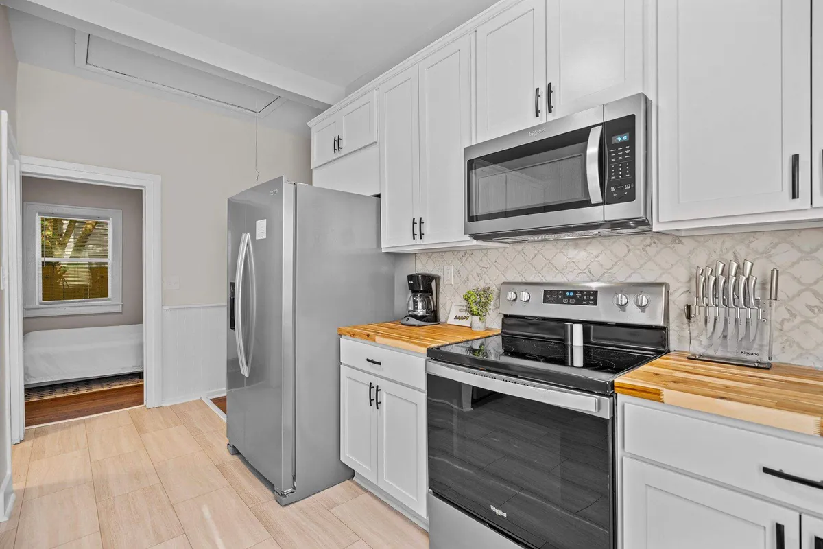 The image showcases a beautifully renovated kitchen featuring gleaming stainless steel appliances, elegant wooden countertops, and sleek modern cabinetry. The space radiates warmth, inviting guests to cook, entertain, and gather around with friends and family.