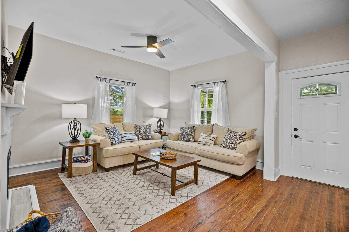 A bright and welcoming living room featuring a comfortable sofa, coffee table, and large windows that let in natural light. The space is arranged for easy conversation, relaxation, and group activities, further emphasizing the open-concept layout.