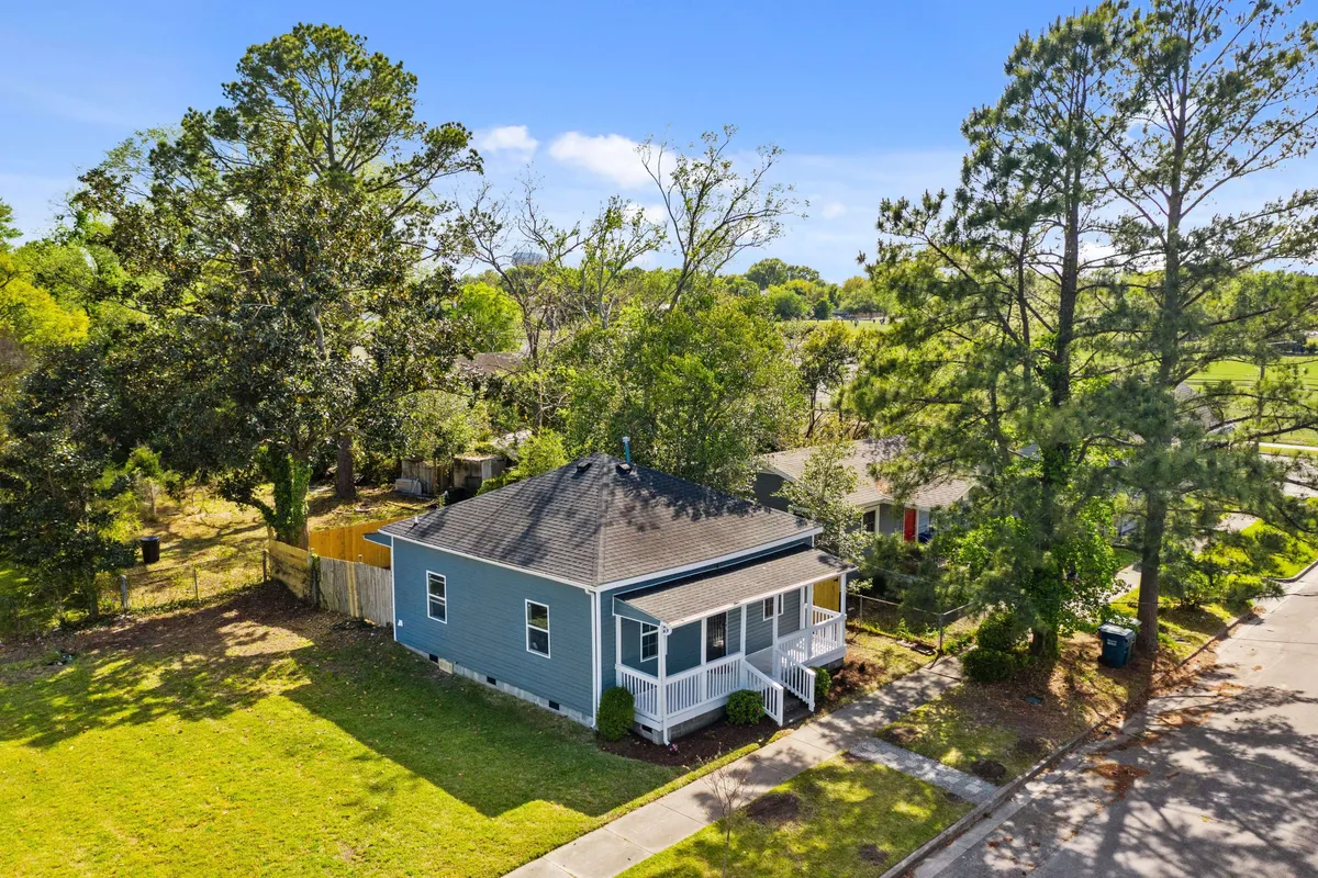 This image captures the front porch of the house surrounded by lush greenery, presenting a welcoming exterior view. The house facade is visible, framed by plants that suggest a tranquil transition space between the lively city and a private retreat.